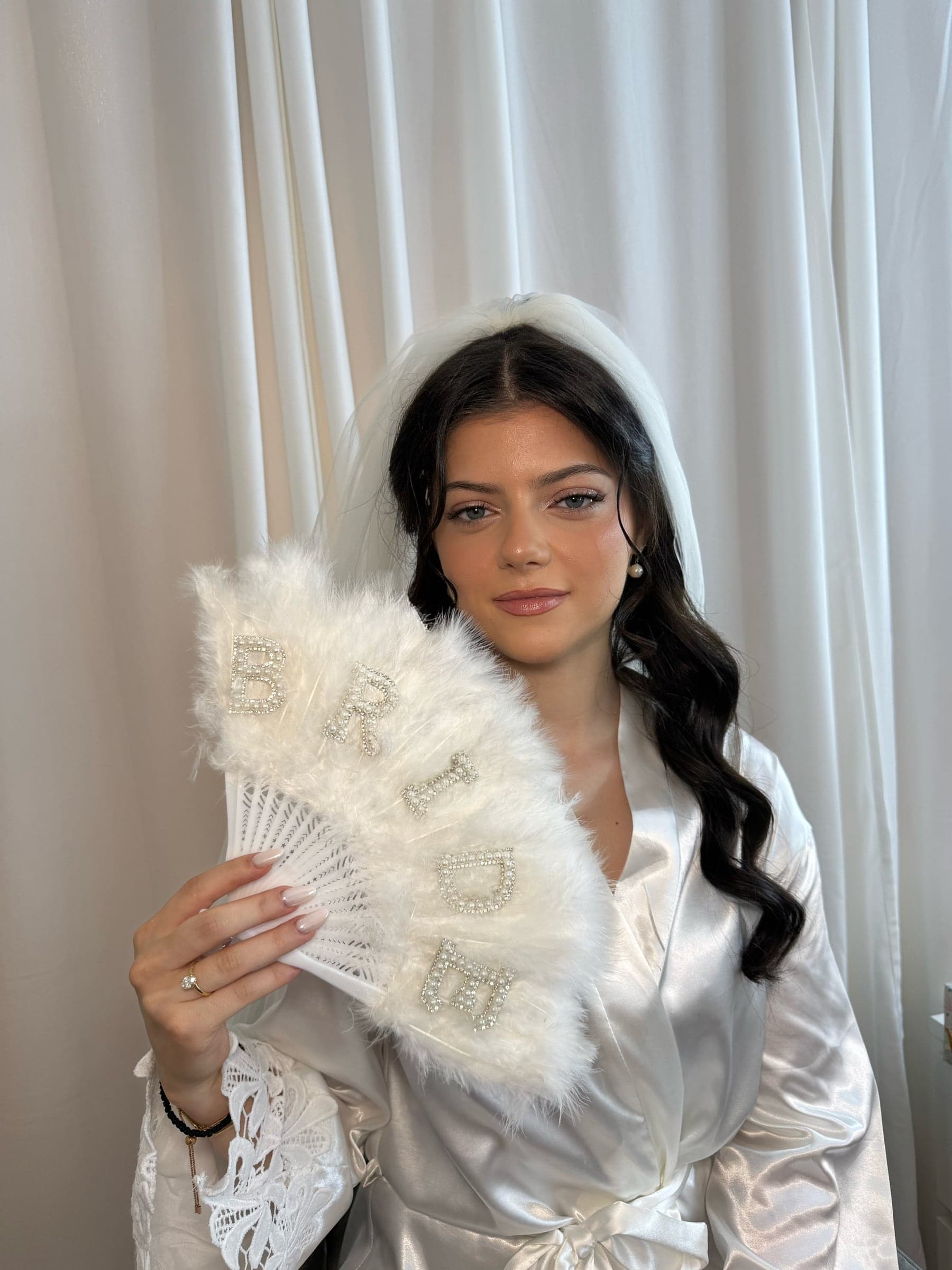 Bride with soft glam makeup holding a bridal fan